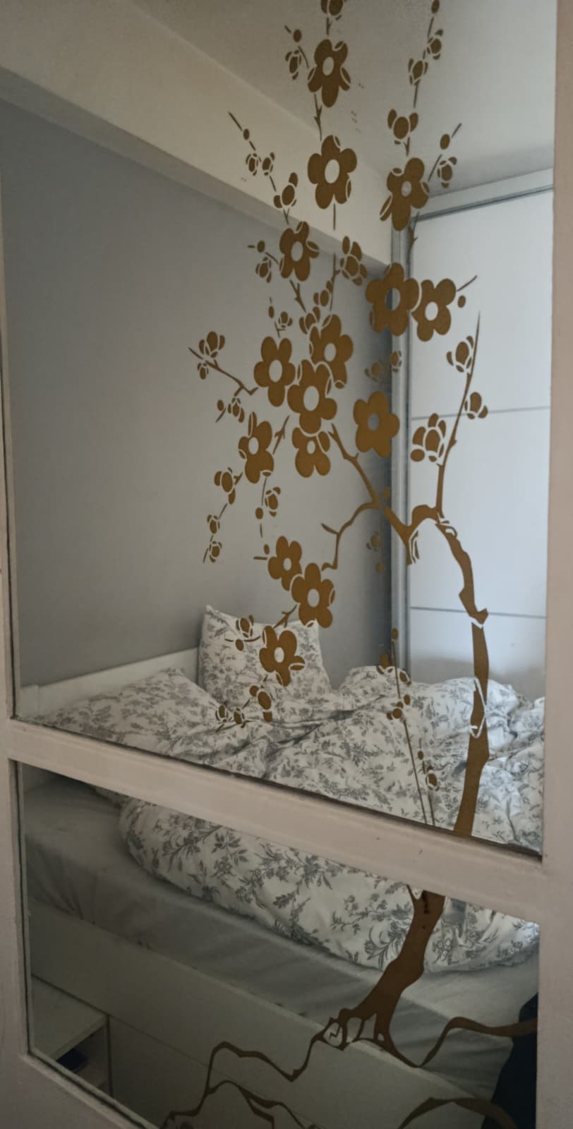 A flowering tree motif on a mirror in an interior space.